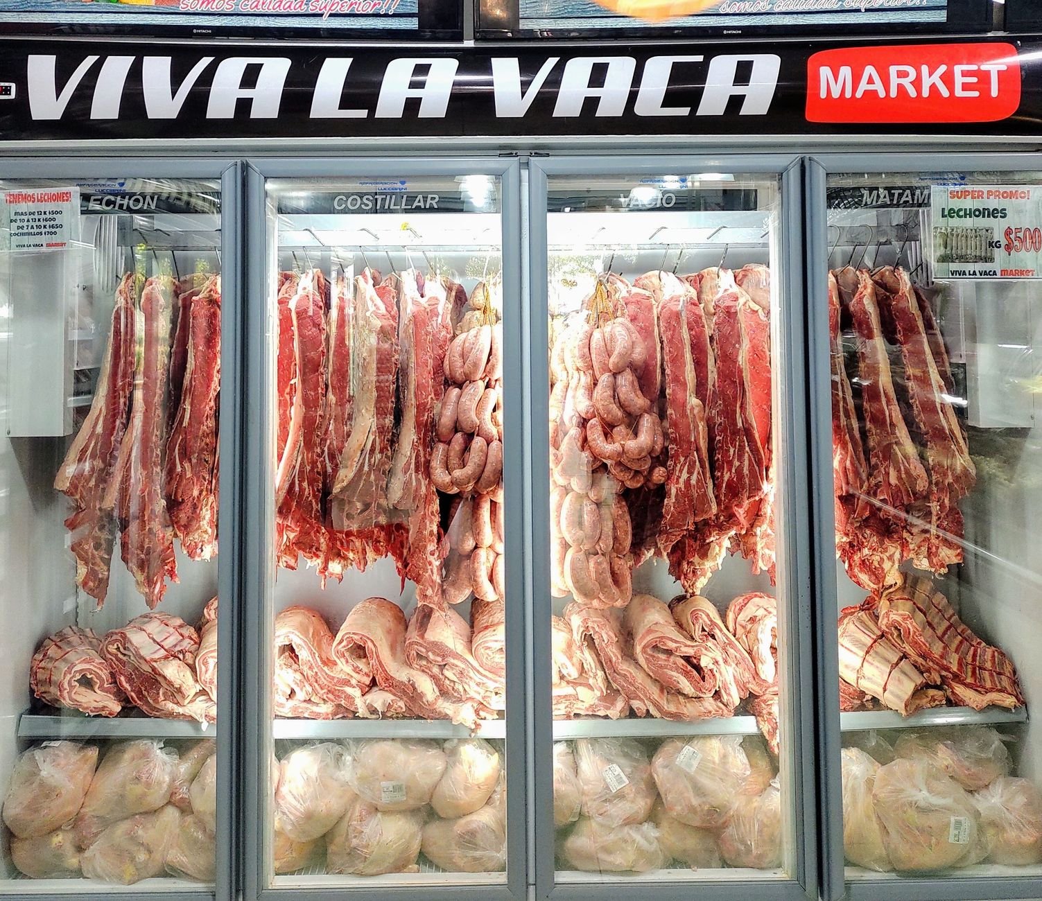 Fresh cuts of meat and sausages laid out in a well-lit refrigerated butcher counter display