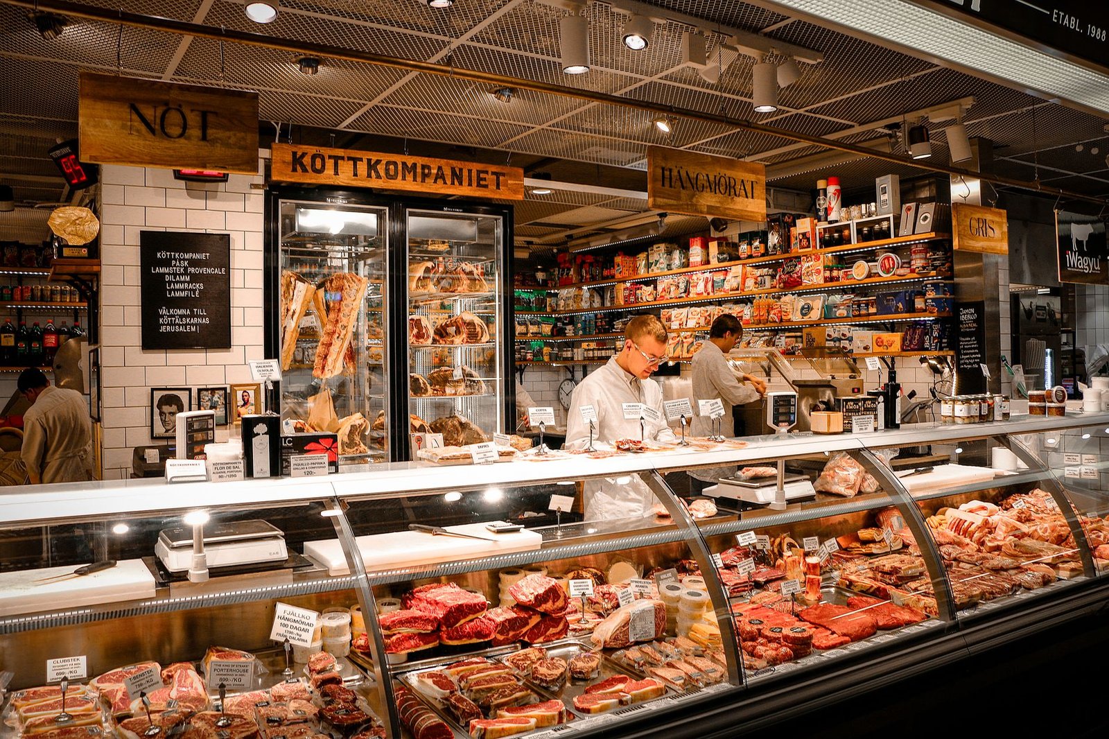 A butcher shop counter displaying fresh cuts of red meat in a refrigerated glass case