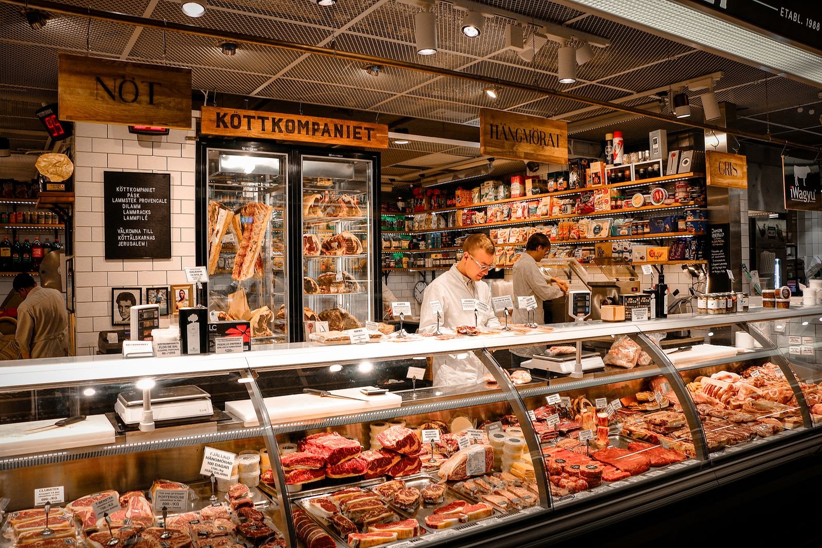 A butcher shop counter with fresh cuts of red meat displayed in a refrigerated glass case